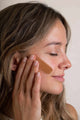 Scoop Whole Beauty model applies HLA infused natural liquid cover pure mineral foundation in shade medium to cheek - medium
