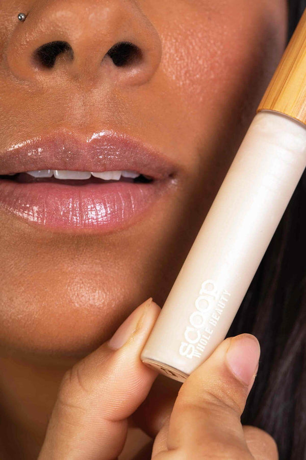 Scoop Whole Beauty model wears natural, non toxic lipgloss in sustainable glass and bamboo packaging in shade clear