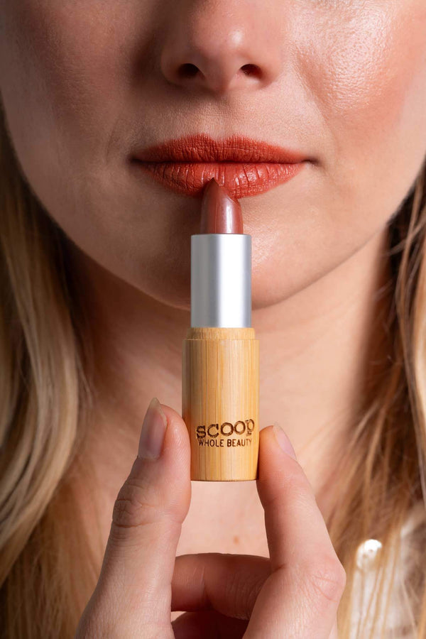 Scoop Whole Beauty model applies natural lipstick in sustainable bamboo tube- peach