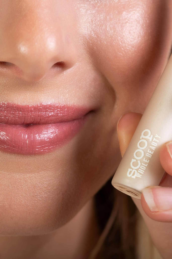 Scoop Whole Beauty model wears natural, non toxic lipgloss in sustainable glass and bamboo packaging- clear