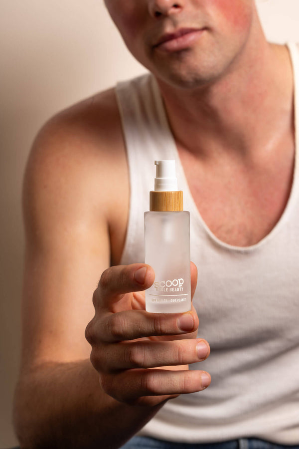 Scoop Whole Beauty male model wears and displays HLA hydrating serum in sustainable packaging