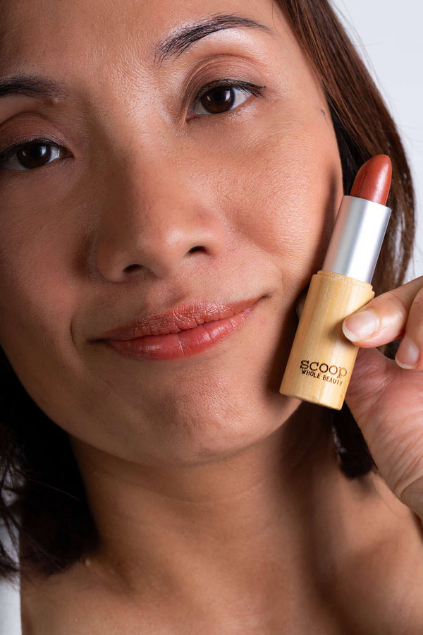 Scoop Whole Beauty model wears natural lipstick in sustainable bamboo tube- peach