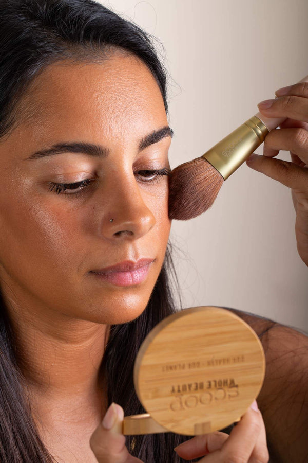 Scoop Whole Beauty model applying natural mineral blusher from sustainable bamboo compact with ultra soft vegan blusher brush