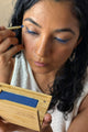 scoop whole beauty model is applying mud cake mascara  compact on her lashes and as an eyeliner