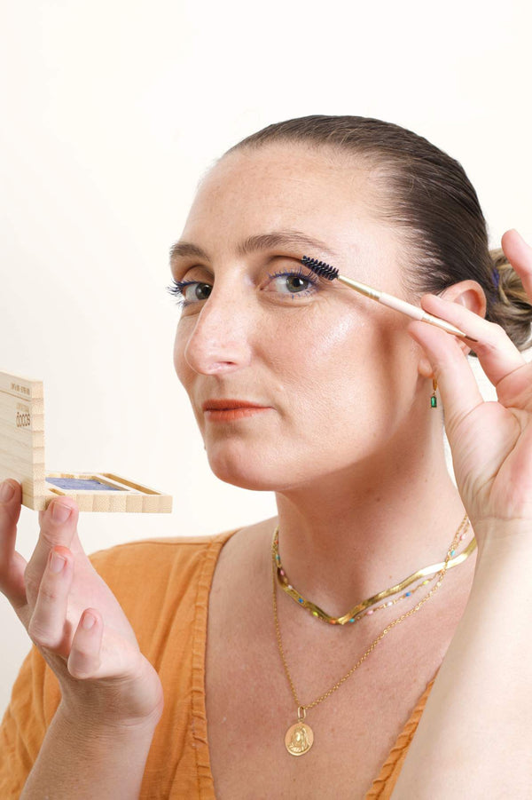 Scoop whole beauty is applying the mud cake mascara on her lashes with the shade ocean blue