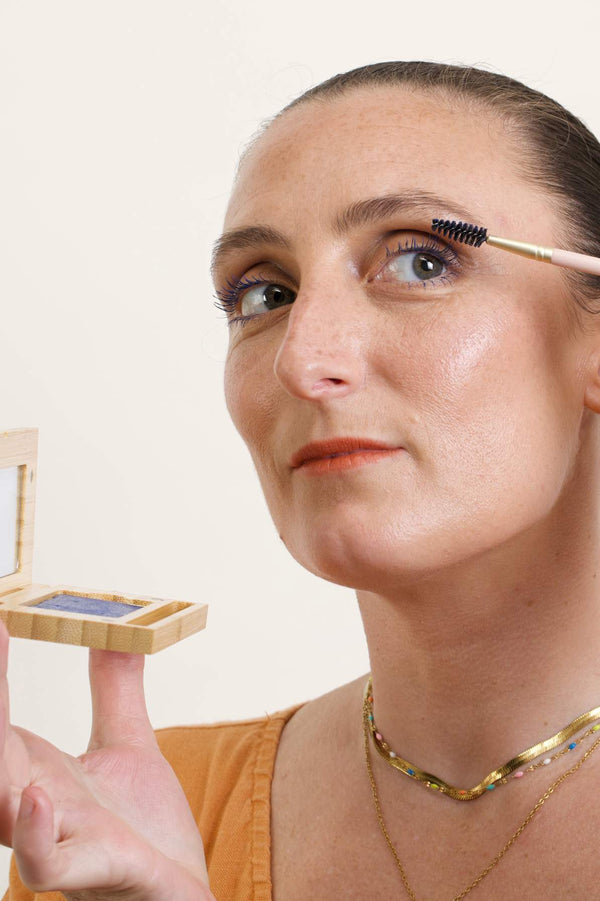 Model is applying the Scoop Whole Beauty's newest shade of Mud Cake Mascara in her eyelashes.