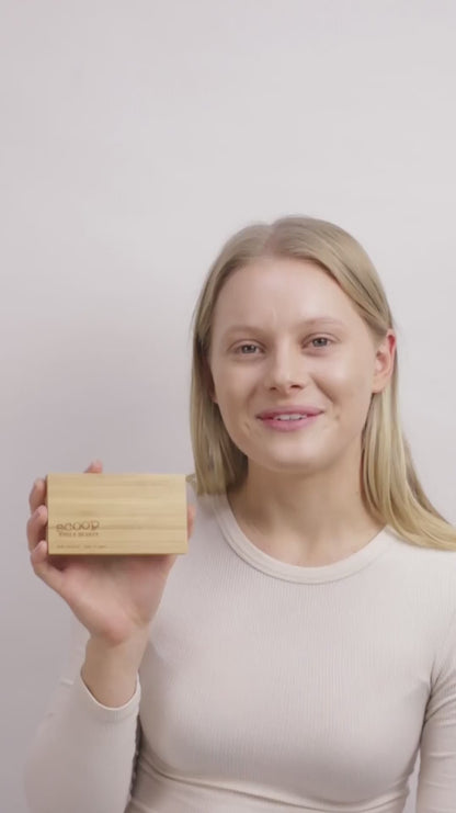 Woman is explaining and demonstrating how to apply the mud cake mascara.