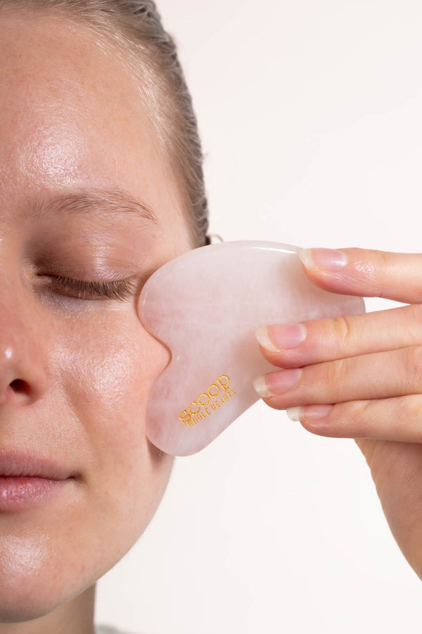 Scoop Whole Beauty model massages face with organic, cold pressed, Australian, jojoba oil and rose quartz gua sha