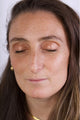The model is closing her eyes, showing the eyeshadow shade Coral in her eyelids.