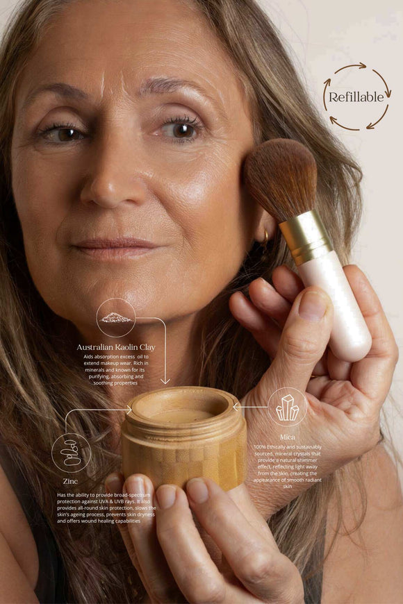 Woman applying scoop whole beauty's pure mineral powder foundation spf 24+ with ultra-soft vegan kabuki brush the the right side of her face and holding the bamboo powder sifter in the right handwith information about the start ingredients of the product